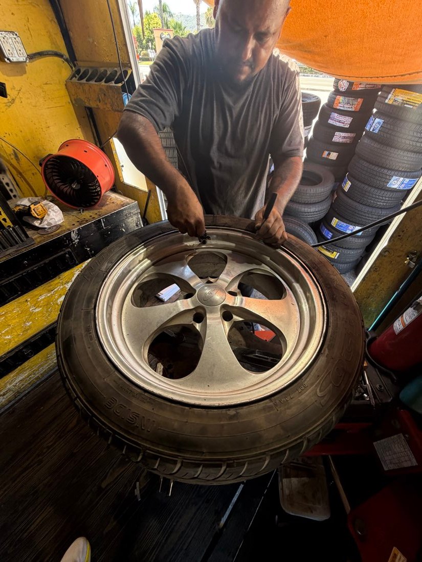 Technician installing a wheel with new tire inventory in the background
