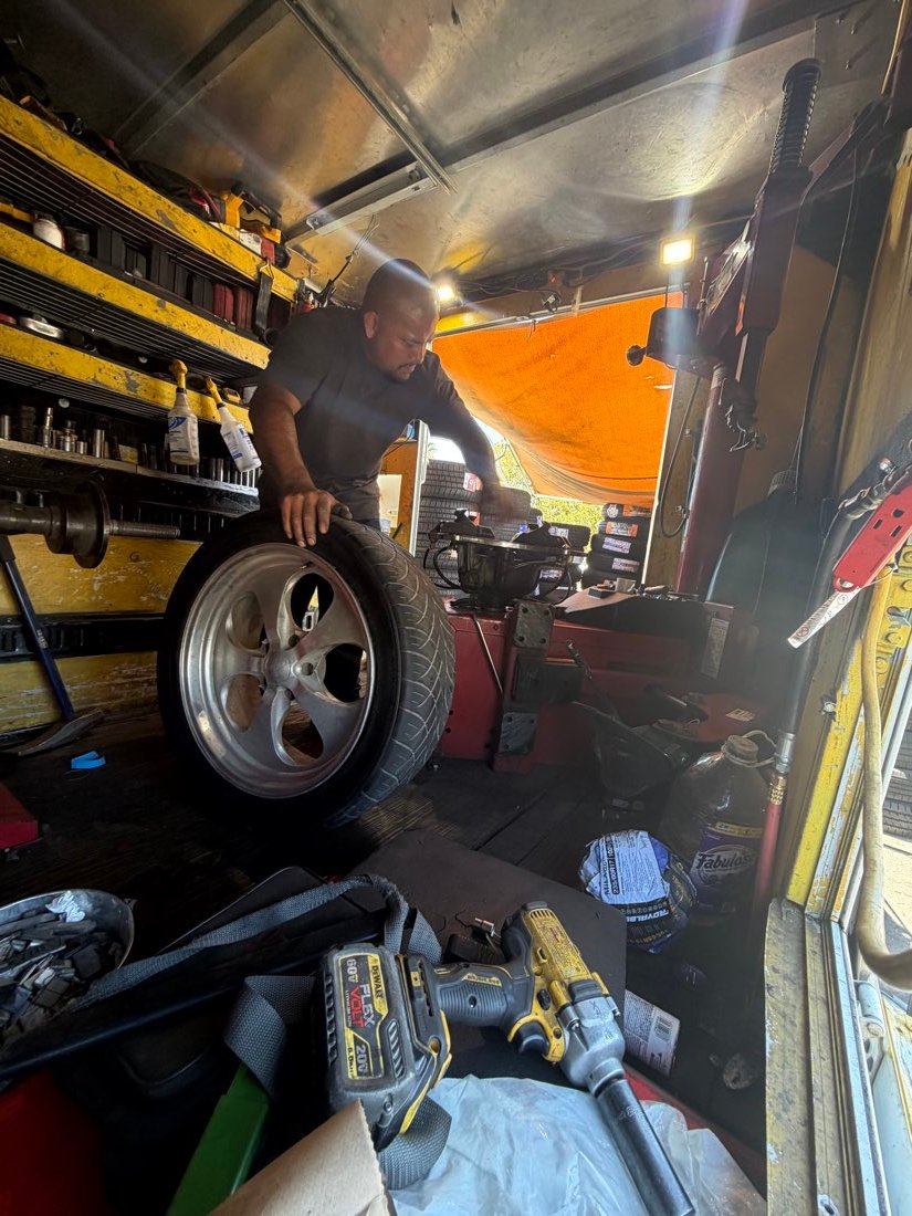 Technician handling a tire next to the tire-changing machine